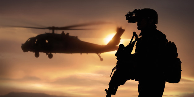 Combat ready special operation forces soldier in an Afghanistan war scene with a black hawk helicopter.