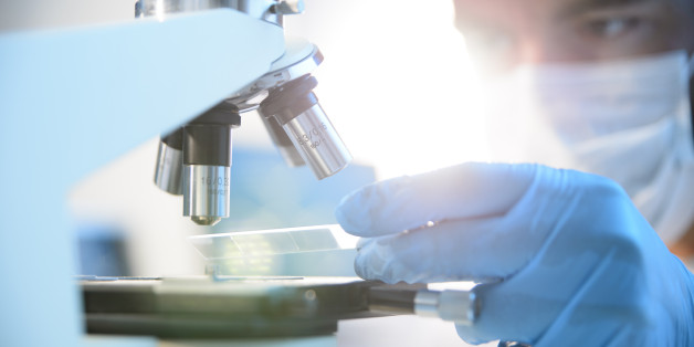 A scientist placing a slide under a microscope