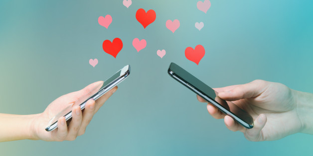 Young man and woman's hands holding smart phones with hearts floating over