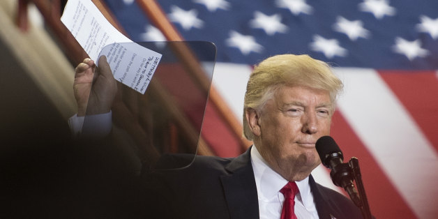 US President Donald Trump (C) holds a copy of the poem 'The Snake' prior to reciting the rhyming verses during a 'Make America Great Again' rally in Harrisburg, PA, April 29, 2017, marking his 100th day in office. / AFP PHOTO / JIM WATSON (Photo credit should read JIM WATSON/AFP/Getty Images)