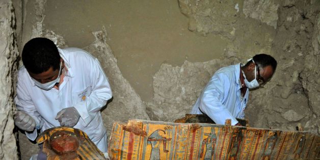 Members of an Egyptian archaeological team work on a wooden coffin discovered in a 3,500-year-old tomb in the Draa Abul Nagaa necropolis, near the southern Egyptian city of Luxor, on April 18, 2017.Egyptian archaeologists have unearthed several mummies, colourful wooden coffins and more than 1,000 funerary statues in the 3,500-year-old tomb, the antiquities ministry said. / AFP PHOTO / STRINGER (Photo credit should read STRINGER/AFP/Getty Images)