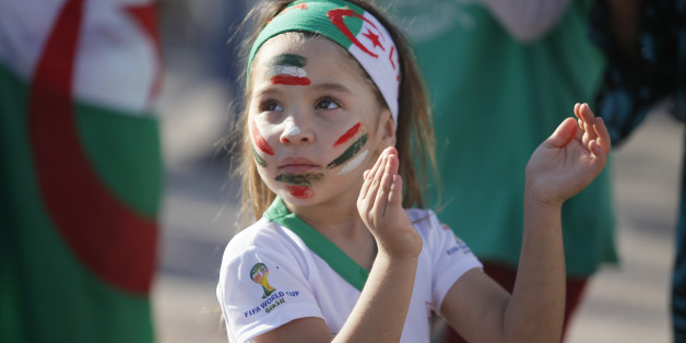 ALGIERS, ALGERIA - JUNE 17: Fans of Algeria watch their national team's soccer match with Belgium during the 2014 FIFA World Cup Group H, on the giant screens at the Al Barid square in different costumes on June 17, 2014 in Algiers, Algeria. A little girl with her painted face is seen at the square. (Photo by Bechir Ramzy/Anadolu Agency/Getty Images)