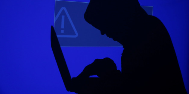 A hooded man holds a laptop computer as blue screen with an exclamation mark is projected on him in this illustration picture taken on May 13, 2017. Capitalizing on spying tools believed to have been developed by the U.S. National Security Agency, hackers staged a cyber assault with a self-spreading malware that has infected tens of thousands of computers in nearly 100 countries. REUTERS/Kacper Pempel/Illustration