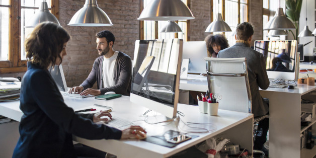 Young people working on a startup office, all are at their desks very concentrated.