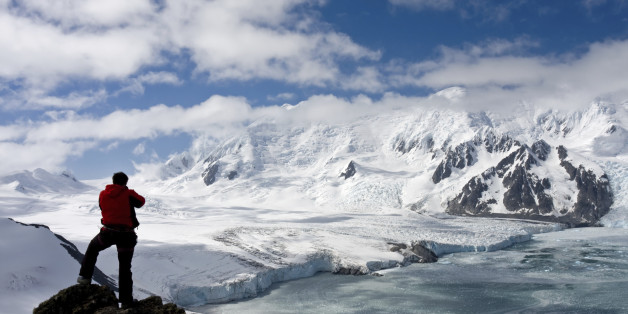 Mountaineer standing on a rock in front of a picturesque mountain range on Livingston Island, Antarctica. The range rises about 1800 meters above the sea level. The highest peak is known as Friesland.