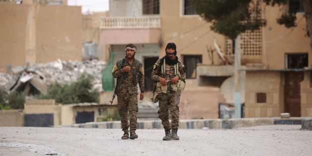 Members of the Syrian Democratic Forces (SDF), walk in the town of Tabqa, about 55 kilometres (35 miles) west of Raqa city, on May 18, 2017.On November 5, 2016, a US-backed alliance of Kurdish and Arab fighters began an operation to capture IS' de facto Syrian capital. On May 10, 2017, the SDF captured the city of Tabqa and an adjacent dam, the last big town before Raqa. / AFP PHOTO / DELIL SOULEIMAN (Photo credit should read DELIL SOULEIMAN/AFP/Getty Images)