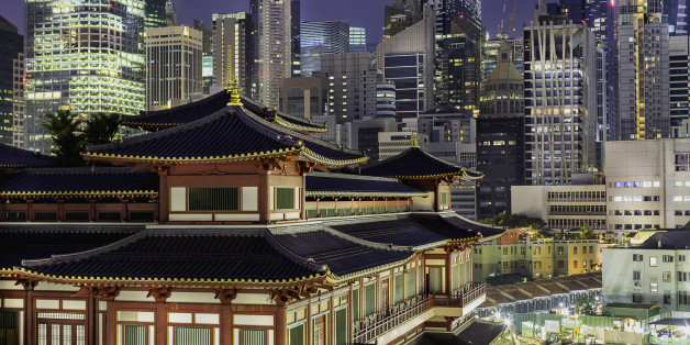 The famous Buddha Tooth Relic Temple in China town, Singapore. A stunning Chinese-style architecture among tall buildings with city lights.