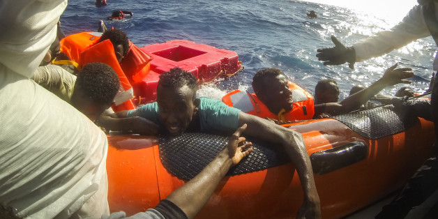 LAMPEDUSA, ITALY - MAY 24: Refugees and migrants are pulled onboard a rescue craft by crewmembers from the Migrant Offshore Aid Station (MOAS) 'Phoenix' vessel after a wooden boat bound for Italy carrying more than 500 people capsized on May 24, 2017 off Lampedusa, Italy. The Migrant Offshore Aid Station (MOAS) 'Phoenix' vessel rescued 603 people after one of three wooden boats partially capsized leaving more than 30 people dead. Numbers of refugees and migrants attempting the dangerous central