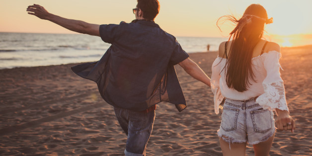 Couple running free on the beach while holding hands