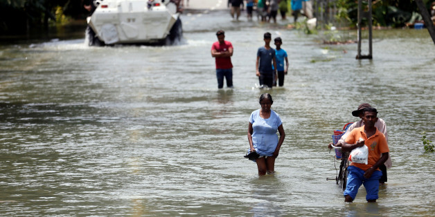 People walk through a flooded road to cross the Bulathsinhala village, in Kalutara, Sri Lanka May 27, 2017. REUTERS/Dinuka Liyanawatte