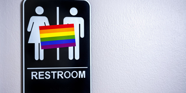 LGBT flag on a restroom sign posted on a wall. There is a lot of controversy over North Carolina's HB2 bill, the Carolina bathroom bill, and other legislation around the US against the LGBT community.