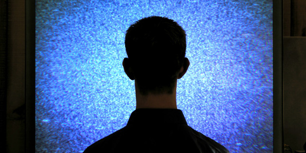 'man watches tv snow. focus is on guy although, he's in the dark. it's supposed to have a dark feel.'