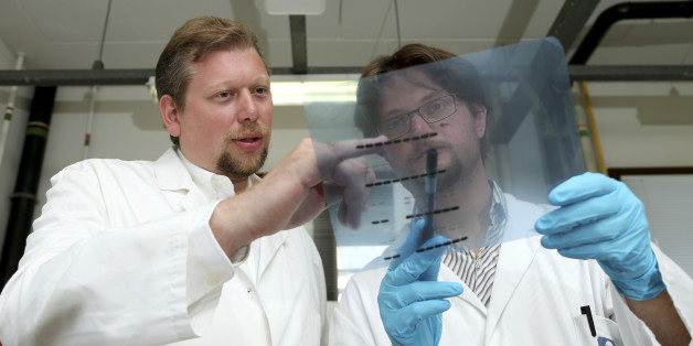 Belgian researcher Pierre Sonveaux stands next to his team member Paolo Porporato (R) of Italy as they examine a readout on a photographic film at the University of Louvain's Institute of Experimental and Clinical Research in Brussels July 31, 2014. According to the institute, the researchers have reached a breakthrough in preventing cancer tumours from spreading. REUTERS/Francois Lenoir (BELGIUM - Tags: HEALTH SOCIETY SCIENCE TECHNOLOGY)