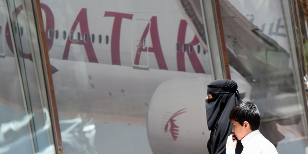 A picture taken on June 5, 2017 shows a Saudi woman and a boy walking past the Qatar Airways branch in the Saudi capital Riyadh, after it had suspended all flights to Saudi Arabia following a severing of relations between major gulf states and gas-rich Qatar.Arab nations including Saudi Arabia and Egypt cut ties with Qatar accusing it of supporting extremism, in the biggest diplomatic crisis to hit the region in years. / AFP PHOTO / FAYEZ NURELDINE (Photo credit should read FAYEZ NURELDIN