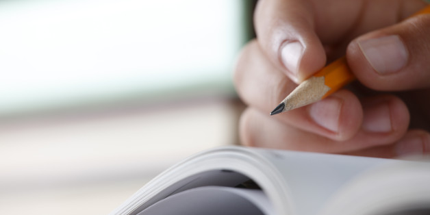 A closeup of a teenager holding a pencil while doing homework. Shot with shallow depth of field.