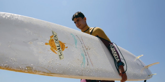 Ali Kassem, a 17-year-old Syrian refugee, carries his surfboard on a beach in the town of Jiyeh, south of the Lebanese capital Beirut, on May 24, 2017.Ali Kassem had never seen the sea before he fled his home in Syria for Lebanon, but now he's a regular in the waves and dreams of his own surf school. / AFP PHOTO / JOSEPH EID (Photo credit should read JOSEPH EID/AFP/Getty Images)