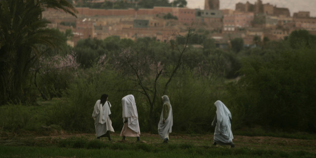Women return to their houses at dusk in Todra Oasis, near Tinerhir March 9, 2009. When some Moroccan rivers start to dry out in the north of the Sahara desert they create spectacular oasis'. Huge palm trees grow around the water, and the Berber people cultivate the surrounding land through channelled irrigation systems. REUTERS/Rafael Marchante (MOROCCO)