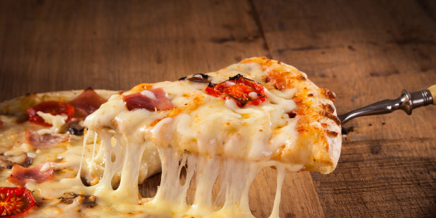 A slice of hot pizza just from the oven with melted cheese dripping