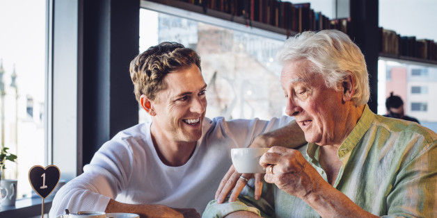 Mature father and son enjoying a coffee together, the son looks proud of his dad and they are chatting happily together.