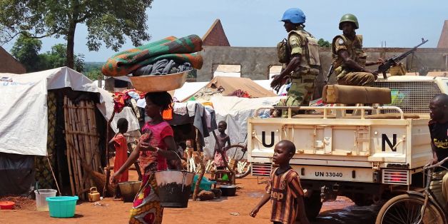 A woman and a child walk past UN peacekeepers from Gabon patrolling the Central African Republic town of Bria on June 12, 2017.
After a renewed flare of violence in the region of Bria, the UN called the Central Africans to find a political solution and international donors to 'keep their promises' of aid. / AFP PHOTO / SABER JENDOUBI (Photo credit should read SABER JENDOUBI/AFP/Getty Images)