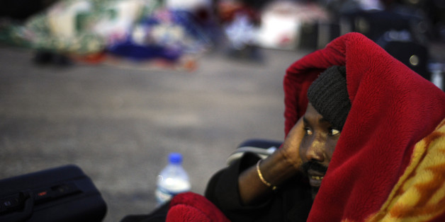 A refugee, who fled from Libya, waits wrapped in a blanket at the border between Libya and Tunisia at the Ras Jedir post on March 11, 2011. Libya's neighbours Tunisia, Algeria and Egypt, mobilised to receive and repatriate a tide of refugees fleeing the unrest, with help from European countries and the United States. AFP PHOTO/ DOMINIQUE FAGET (Photo credit should read DOMINIQUE FAGET/AFP/Getty Images)