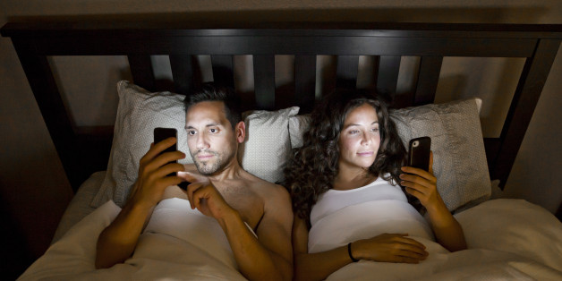 Young couple on their phones in bed.