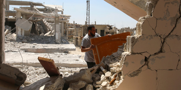 A man gathers his belongings from damaged houses inside a former Palestinian refugee camp in a rebel-held part of the southern city of Deraa, Syria June 18, 2017. REUTERS/ Alaa al Faqir
