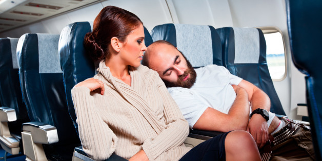 Disgusted woman looking at the sleeping man sitting next to her, who rests his head on her shoulder.