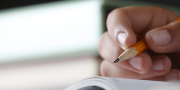 A closeup of a teenager holding a pencil while doing homework. Shot with shallow depth of field.