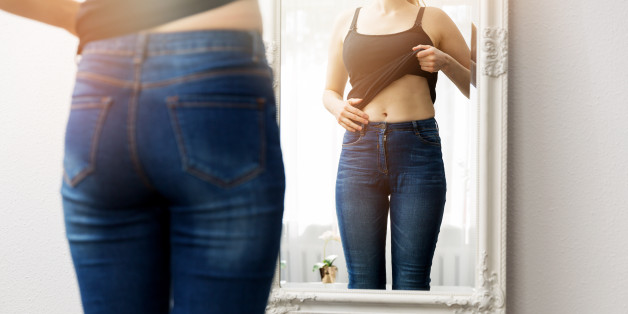 woman checking her body in front of mirror