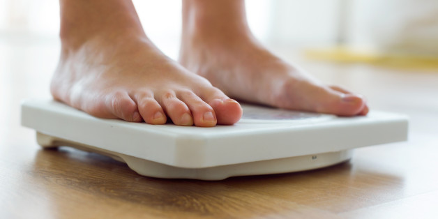 Portrait of young healthy girl on home scales.