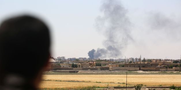 A member of the Syrian Democratic Forces (SDF), made up of an alliance of Kurdish and Arab fighters, looks at smoke rising in the al-Meshleb neighbourhood of Raqa as they try to advance further into the Islamic State (IS) group's Syrian bastion, on June 7, 2017 two days after finally entering the northern city.The SDF alliance began the battle for the city earlier this week after seven months of fighting to surround the key jihadist stronghold. / AFP PHOTO / DELIL SOULEIMAN (Photo credit