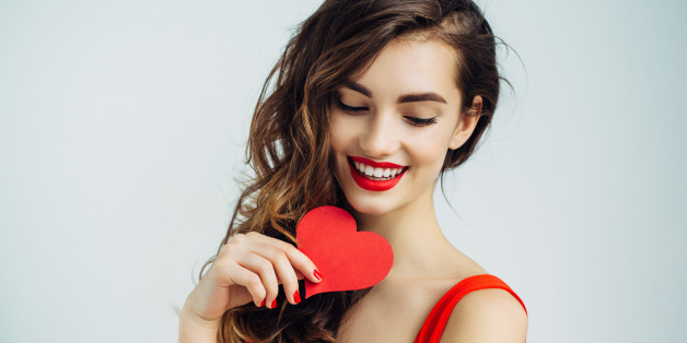 Studio shot of young beautiful woman holding artificial heart. Professional make-up.