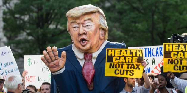 Protesters hold signs and an effigy of US President Donald Trump as he arrives at the Trump International hotel in Washington, DC, on June 28, 2017 to attend a fundraiser for his 2020 campaign. / AFP PHOTO / NICHOLAS KAMM (Photo credit should read NICHOLAS KAMM/AFP/Getty Images)