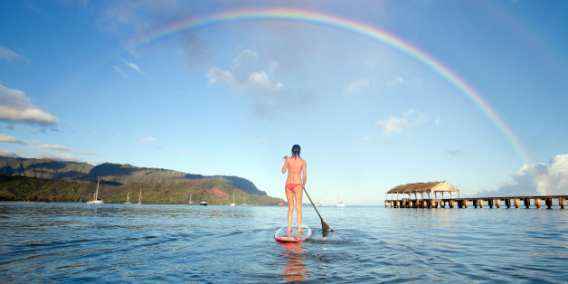 Stand up paddle board in hanalei bay with rainbow in Kauai, Hawaii, USA