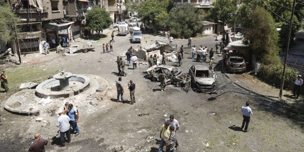 Syrians gather to inspect the damage at the site of a suicide bomb attack in the capital Damascus' eastern Tahrir Square district, on July 2, 2017. Syrian state television reported that security forces had intercepted three suicide car bombers on their way into the city, killing two, but the third managed to reach the eastern Tahrir Square district. The attacker was surrounded but was able to detonate a bomb, killing a number of people and wounding several more, it reported. / AFP PHOTO / LOUAI