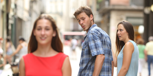 Disloyal man walking with his girlfriend and looking amazed at another seductive girl