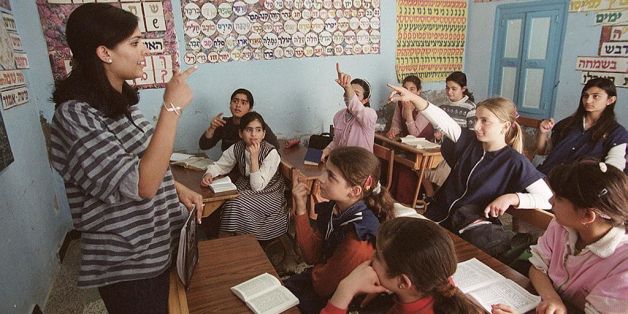 A teacher is conducting her regular classes in front her pupils at the Djerba synagogue in Djerba, south Western Tunisia 12 April 2002, a day after the crash and explosion of a natural gas tanker outside the synagogue, killing 10 people and leaving dozens of others wounded. AFP PHOTO / FEHTI BELAID (Photo credit should read FETHI BELAID/AFP/Getty Images)