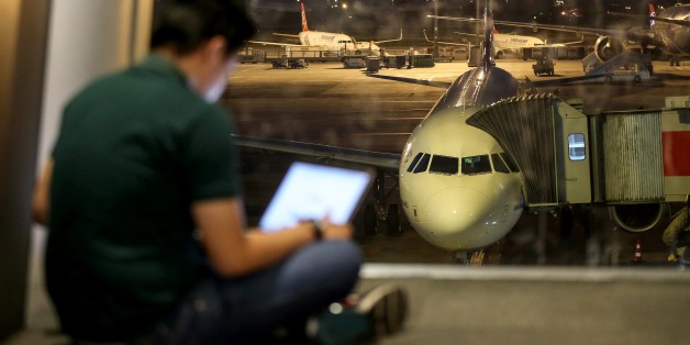 ISTANBUL, TURKEY - MARCH 22: A man checks his tablet computer at the departures lounge as an airliner is seen parked at the apron in the background at Ataturk International Airport in Istanbul, Turkey on March 22, 2017. United Kingdom's flag carrier airline British Airways has started to implement a ban which had issued by British government on all direct flights from the airports in Turkey, Lebanon, Egypt, Saudi Arabia, Jordan and Tunisia. The British government's ban applies to any electronica