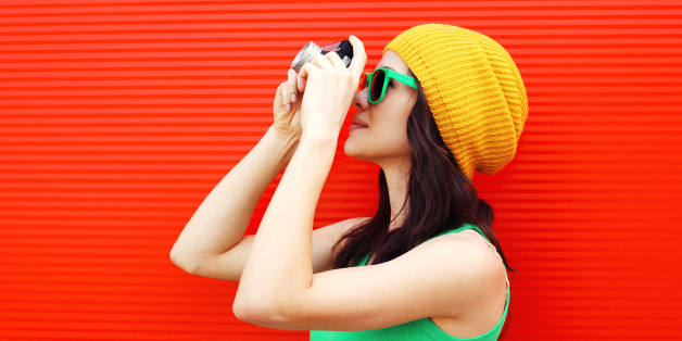 Fashion pretty cool girl wearing a colorful clothes with old retro camera shooting in the city