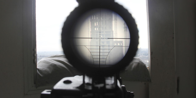 A view seen through the scope of a weapon belonging to a sniper and rebel fighter shows a building where forces loyal to Syria's President Bashar al-Assad are stationed, as seen from a rebel-controlled area in the northwestern Homs district of Al Waer February 18, 2015. Picture taken February 18. REUTERS/Stringer (SYRIA - Tags: MILITARY POLITICS CIVIL UNREST CONFLICT TPX IMAGES OF THE DAY)