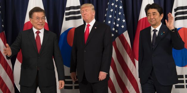 US President Donald Trump (C), Japanese Prime Minister Shinzo Abe (R) and South Korean President Moon Jae-in pose for photos before attending the Northeast Asia Security Dinner at the US Consulate General Hamburg on the sidelines of the G20 Summit in Hamburg, Germany, July 6, 2017.Leaders of the world's top economies will gather from July 7 to 8, 2017 in Germany for likely the stormiest G20 summit in years, with disagreements ranging from wars to climate change and global trade. / AFP PHOTO / SA
