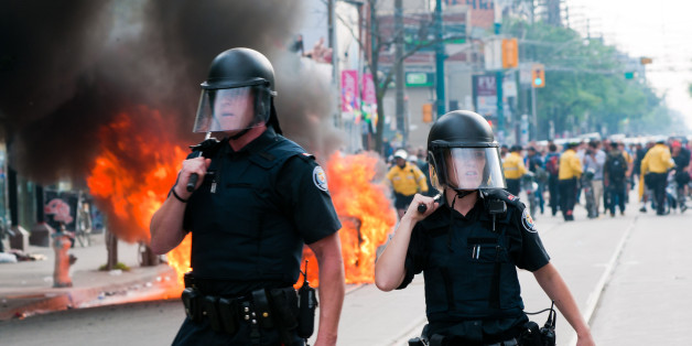 Toronto, Canada - June 26, 2010: A male and female police officer standing in front of a burning police car. Taken during the G20 riots in Toronto, Canada on June 26th, 2010. Several police cars were lit on fire in the city's downtown core in protest of the G20/G8 summits.