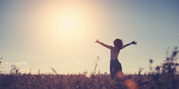Silhouette of a girl enjoying sunset in the field (intentional sun glare and vintage color)