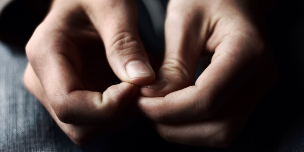 A pair of hands placed anxiously in a lap with natural colors and lighting.
