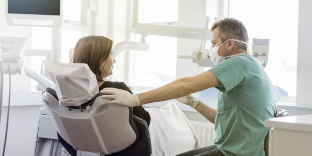 Doctor looking at female patient. Dentist is explaining woman. They are in dental office.