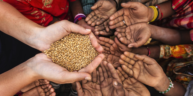 Volunteer caucasian woman giving grain to starving African children. Poor African children keeping their hands up - asking for food. Many African children suffer from poverty - 20% of Africaâs children will die before the age of five. Every day 30,000 children die from a combination of disease- infested water and malnutrition.