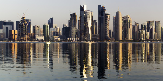 Early morning sunrise golden light hits the city of Doha in Qatar. A wide angle view from across the bay including a typical dhow.