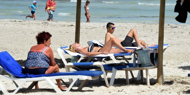 Tourists sit on the beach on the Tunisian resort island of Djerba on May 26, 2016. / AFP / FETHI BELAID (Photo credit should read FETHI BELAID/AFP/Getty Images)