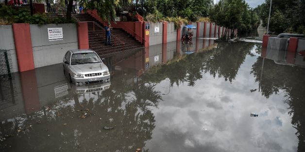 A man takes pictures of a car in a flooded street at the Bayrampasa metro station on July 18, 2017 in Istanbul, following a heavy rainfall. / AFP PHOTO / OZAN KOSE (Photo credit should read OZAN KOSE/AFP/Getty Images)